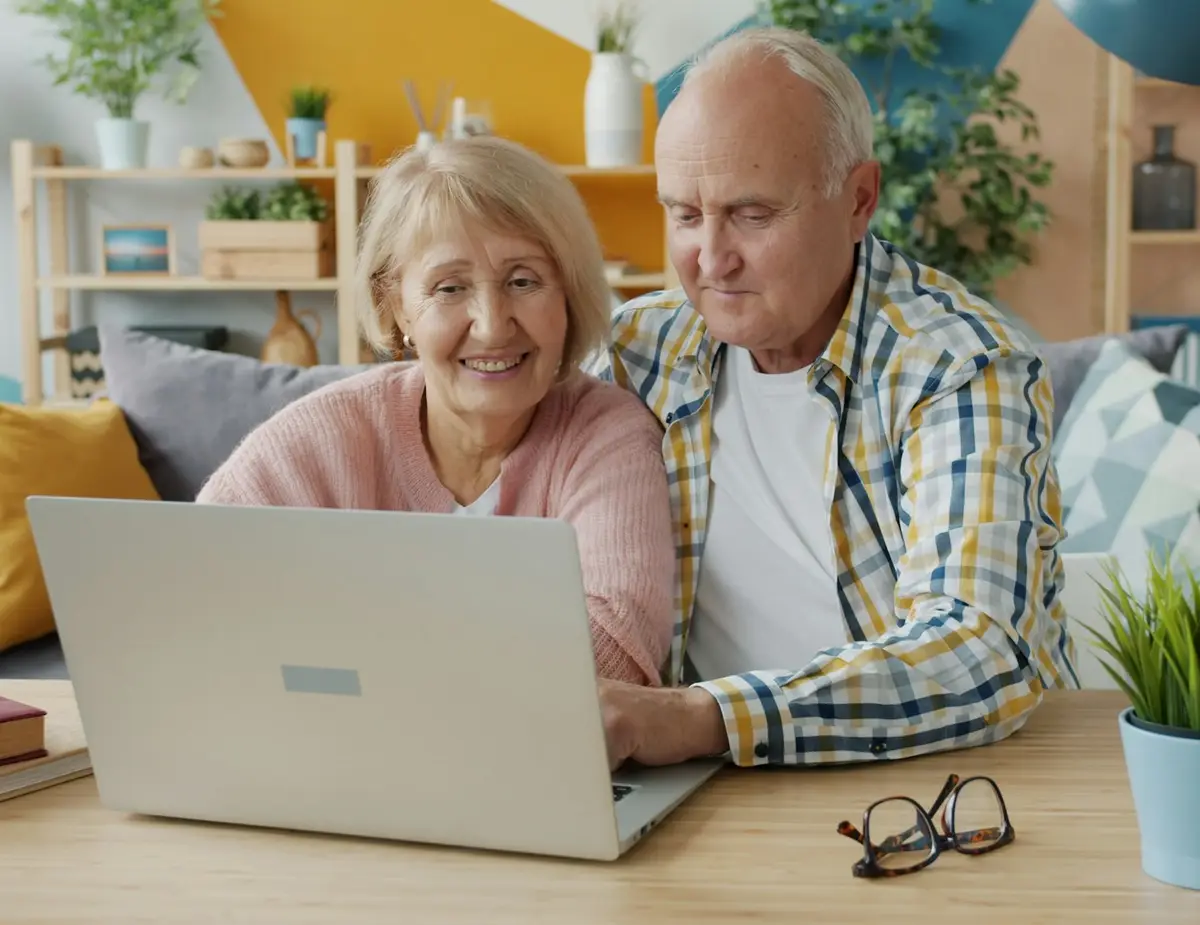 Älteres Ehepaar vergleicht gemeinsam am Laptop und lächelt